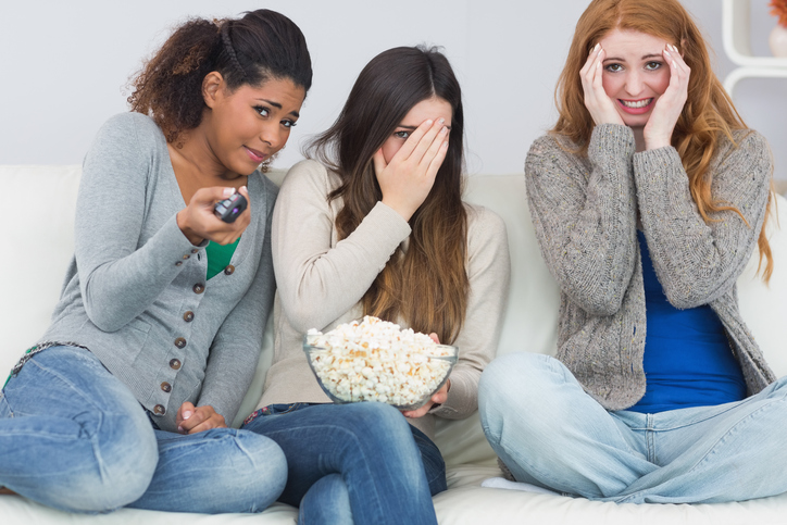 Tri devojke su uplašene, gledaju zastrašujući film, kokice u činiji
