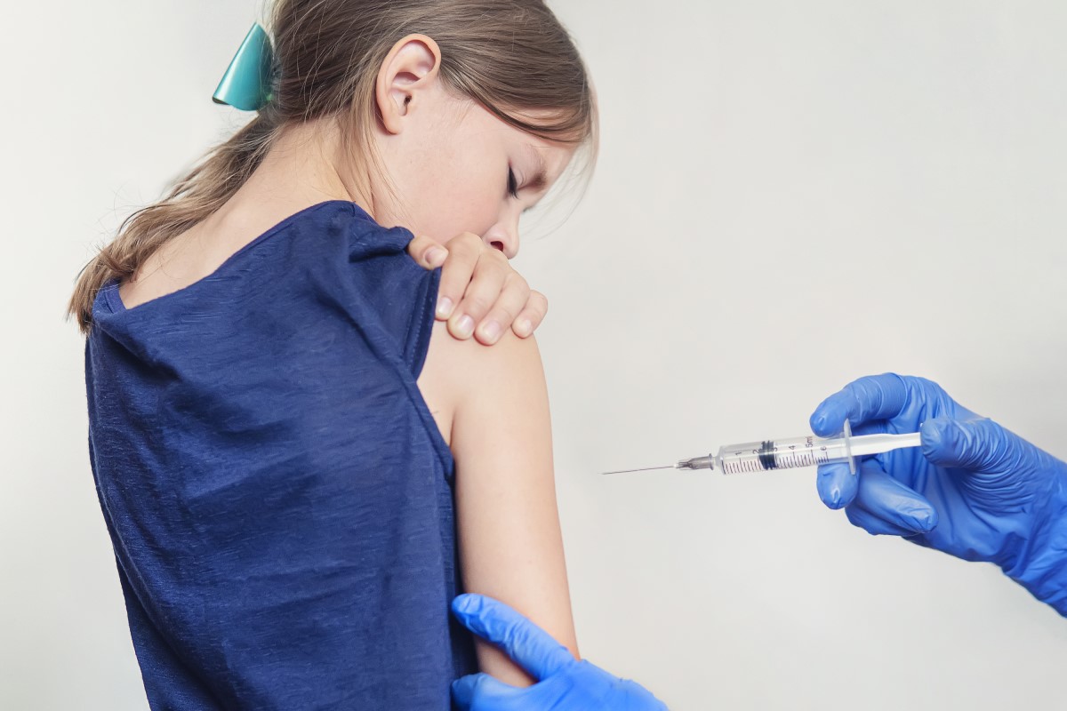 Vakcinacija deteta - devojčice - lekar ubrizgava vakcinu u ruku.