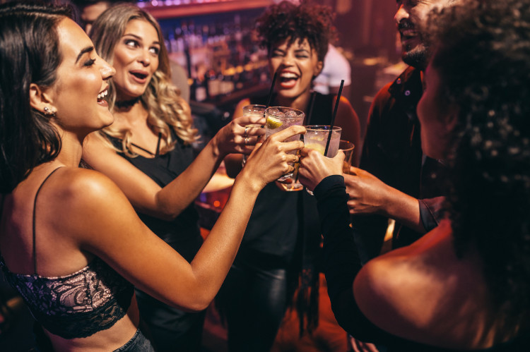 Mladí ľudia, spoločnosť a akloholické nápoje. Zdroj foto: Getty images partia smejúcich sa mladých ľudí v podniku s alkoholom