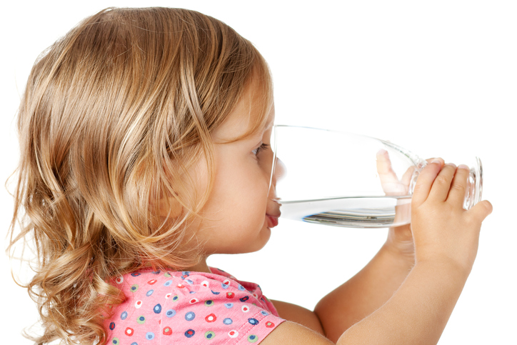 Malé dievčatko pije čistú vodu z pohára