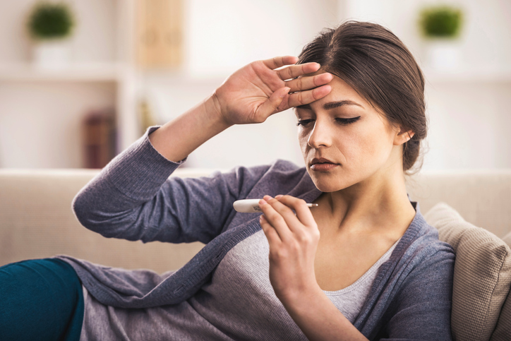 Informácie o výskyte legionelly nie sú presné, nakoľko býva legionelóza často diagnostikovaná len ako zápal pľúc. Foto: Thinkstock Žena držiac sa za čelo, kontrolujúca teplomer v ruke.