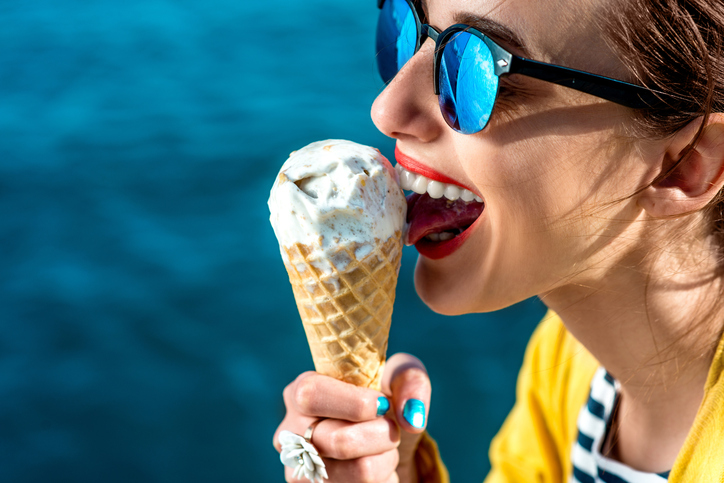 Chlad spôsobuje rozpálenému telu šok, znižuje obranyschopnosť organizmu a ten sa stáva náchylnejším na vznik infekcie. Foto: Thinkstock žena v slnečných okuliaroch líže zmrzlinu vedĺa vody