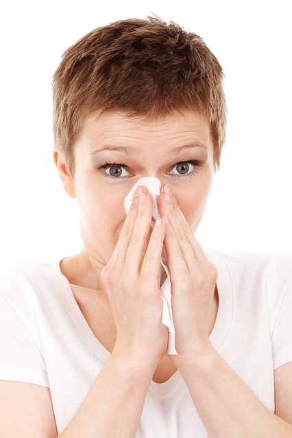 Žena izduvava nos, prehlađena je